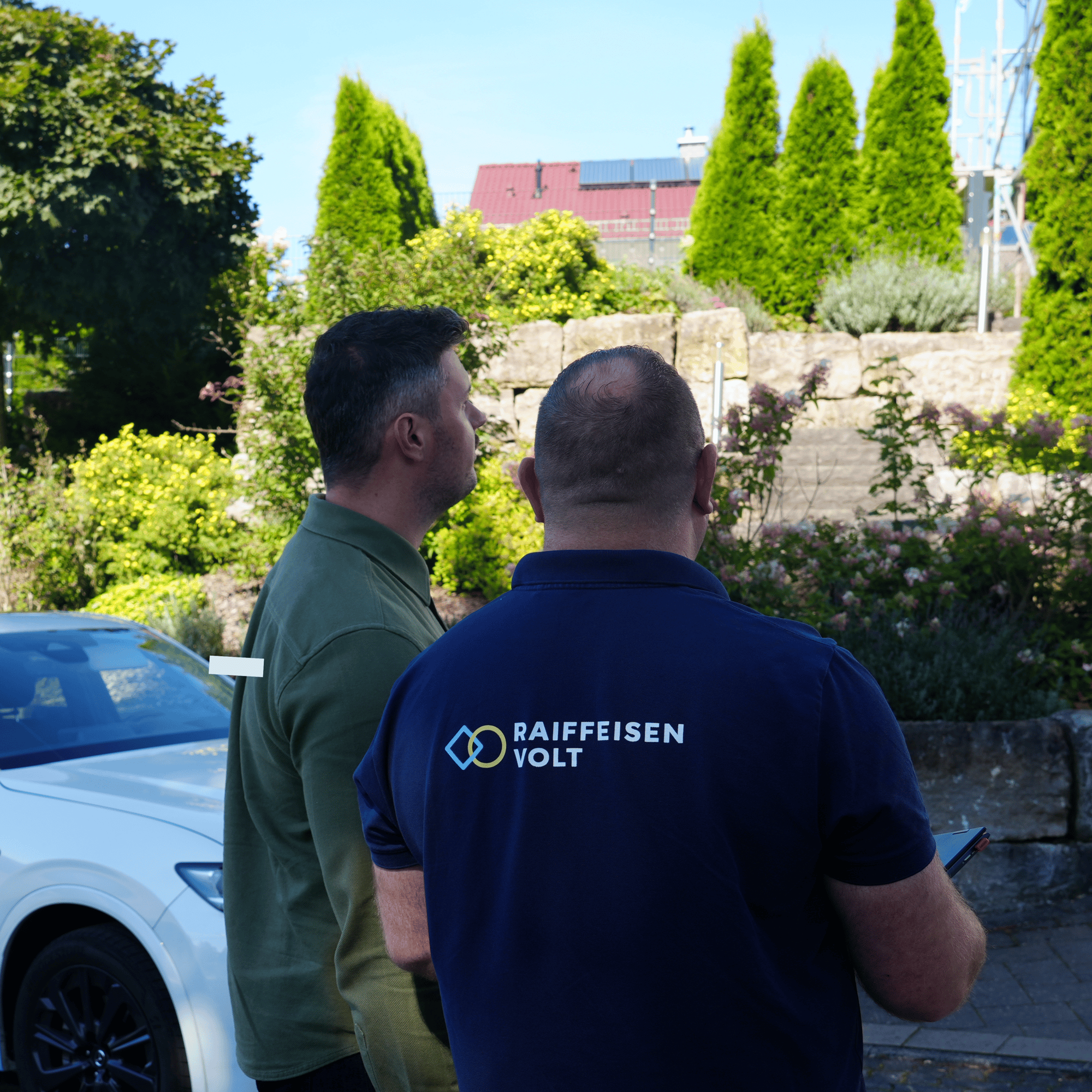 Vertriebsmitarbeiter schaut mit dem Kunden auf die fertig montierte Photovoltaikanlage