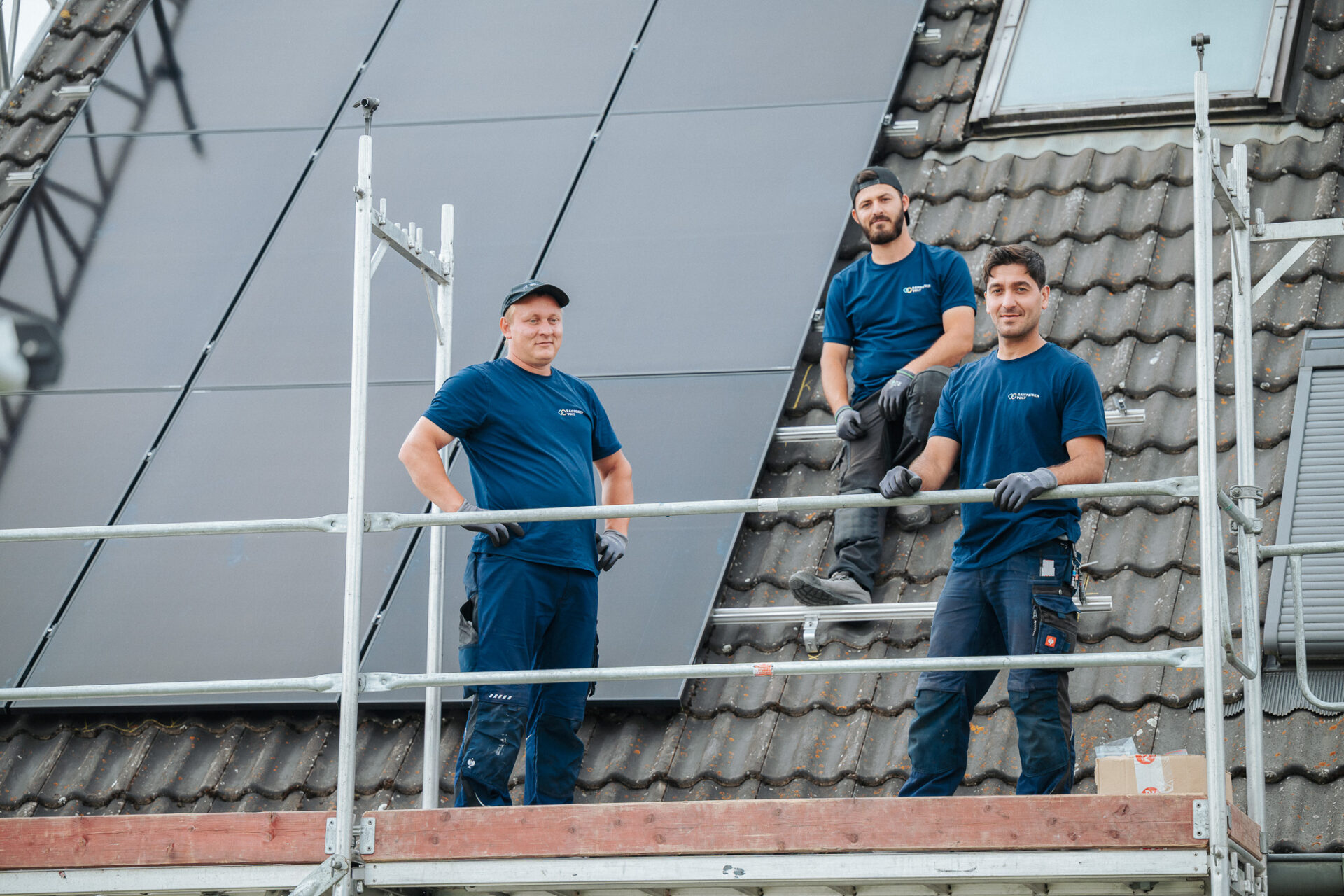 DC-Team von RaiffeisenVolt neben Photovoltaik-Anlage auf Dach