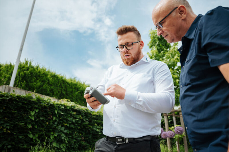 Photovoltaik Experte Janik erklärt Kunden das Vorgehen mittels Drohne