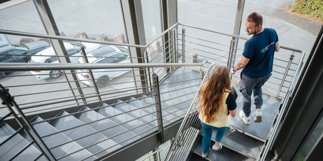 Mitarbeitende von RaiffeisenVolt gehen durch Treppenhaus des Bürogebäudes